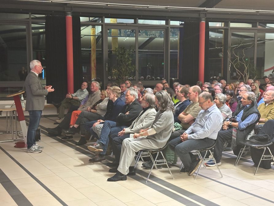 Prof. Dr. Burkert vor seinem Auditorium in der voll besetzten Fraunhofer-Pausenhalle  