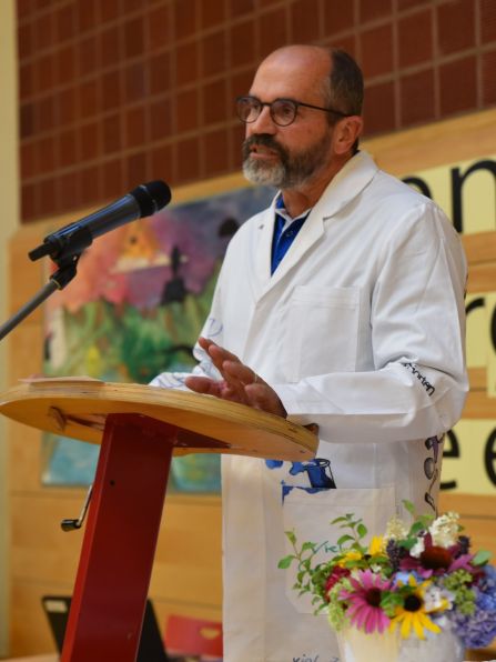 Der scheidende Schulleiter Dr. Hubert Balk bei seiner Abschiedsrede vor der gesamten Schulfamilie - stilgetreu im weißen Laborkittel.