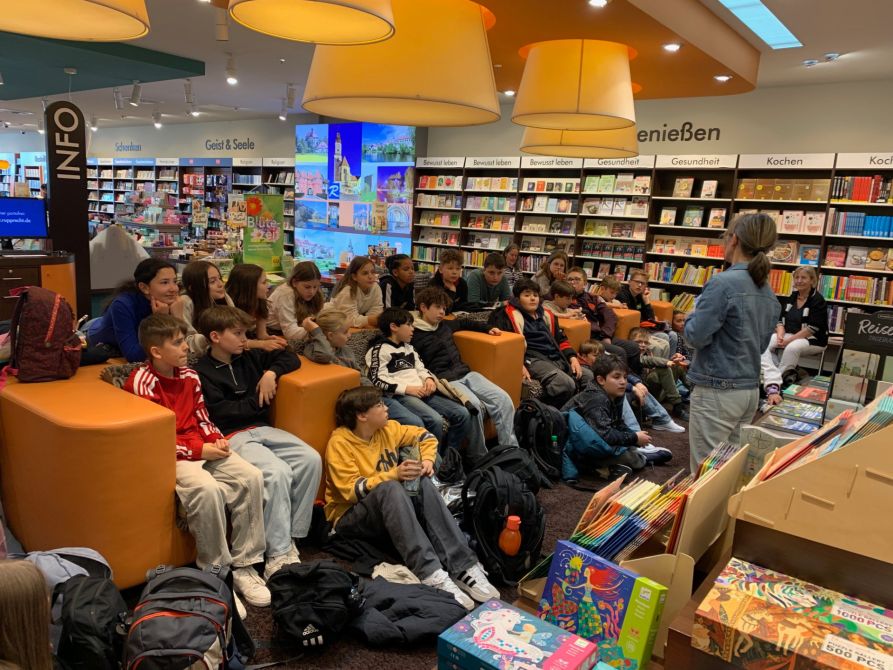 Die Klassen 5a und 5b hatten es sich in der Buchhandlung gemütlich gemacht und hörten gebannt der Buchhändlerin, Evi Heitzer, zu.