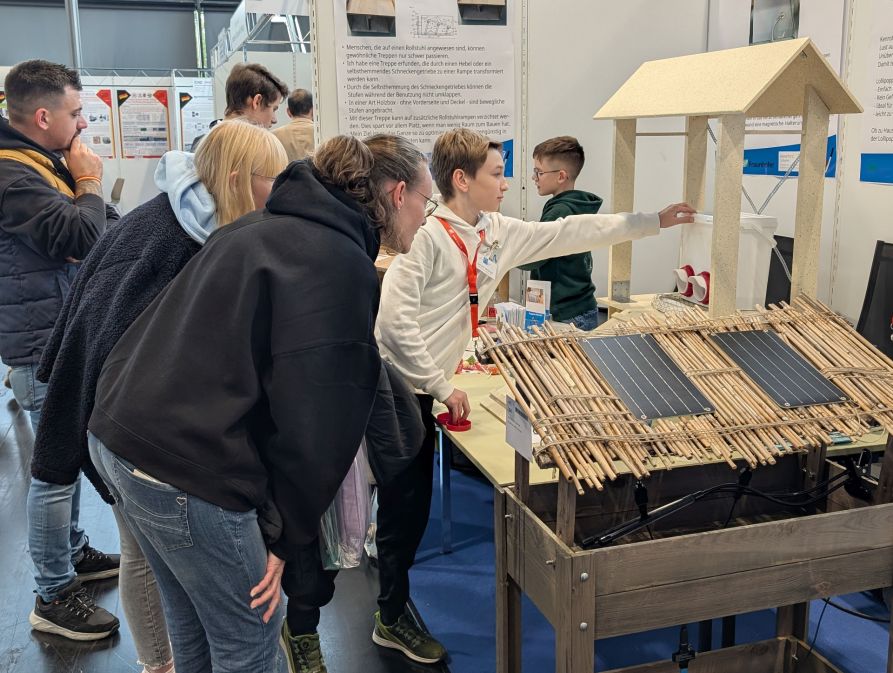 Samuel Heuberger erklärt Besuchern seinen verbesserten Fressplatz für Hühner.