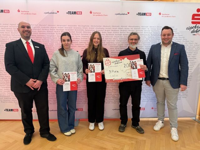 Eva und Laura werden bei der Siegerehrung von ihrem WR-Lehrer Herrn Peter Borowitz und Herrn Maximilan Frank (Abteilungsleiter Wertpapiere der Sparkasse) rechts und von Herrn Mario Schlegl (in Vertretung für den Filialdirektor der Direktion Cham) links eingerahmt. 