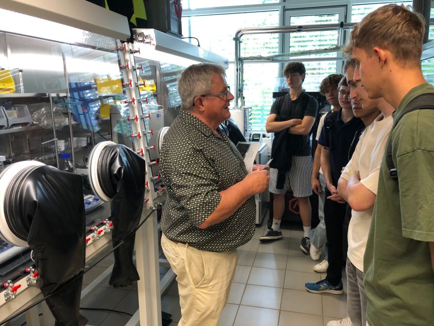 Prof. Breu erklärt den Schülerinnen und Schülern den Aufbau von neuen Batterie-Zellen.